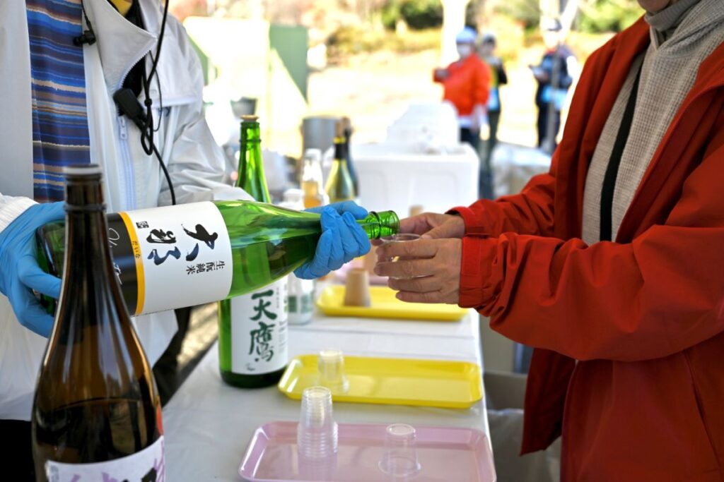 ONSEN・ガストロノミーウォーキング in 那須塩原2025で、日本酒を受け取る様子